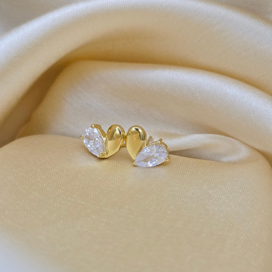 Gold earring with clear gemstones on a beige fabric background