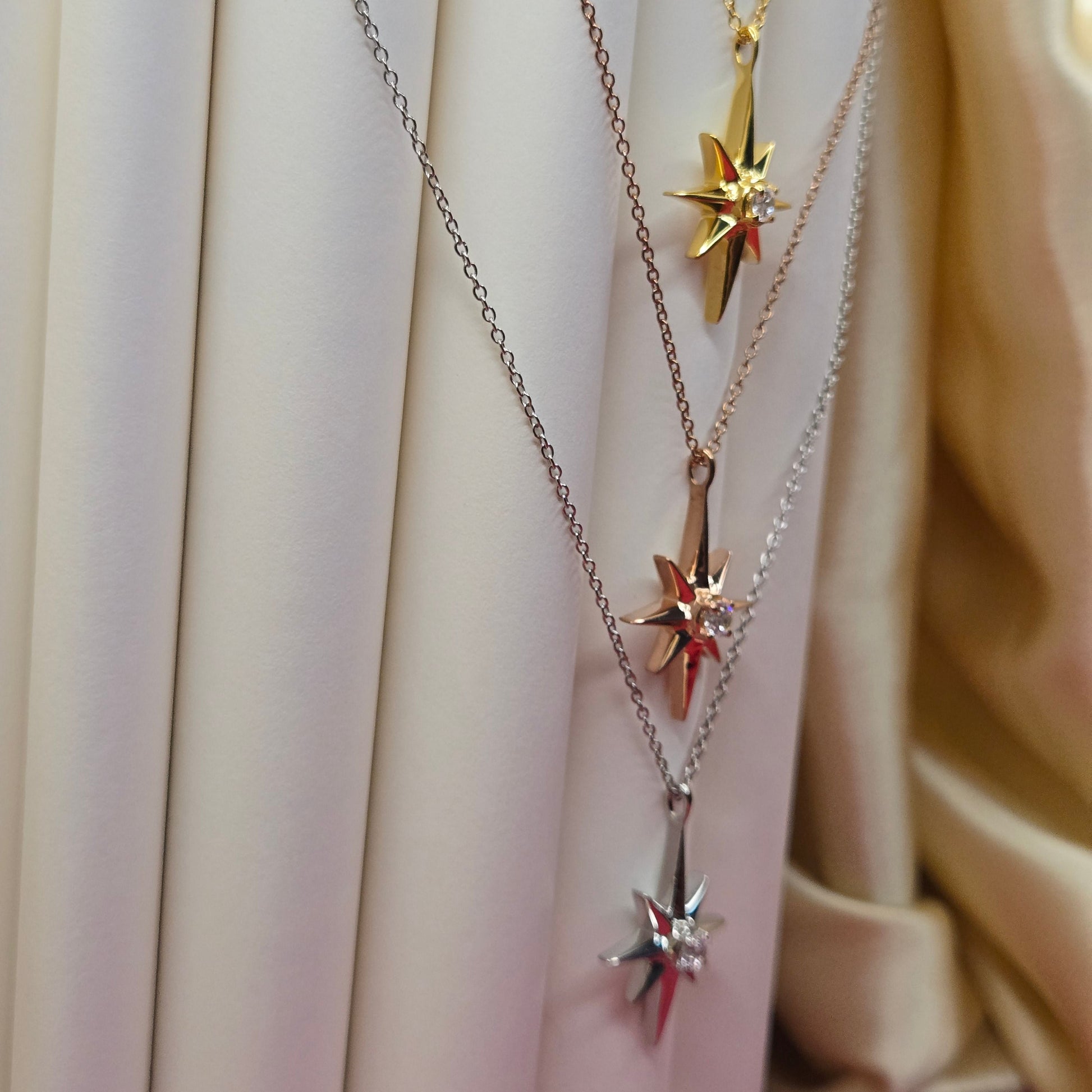 Gold, rose gold, rhodium plated chain necklace featuring an eight-point starburst pendant with a clear faceted crystal at the center, offering a celestial and minimal everyday style