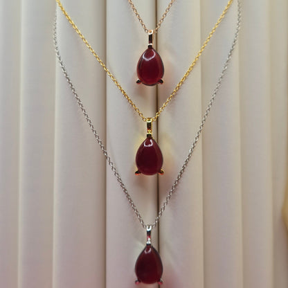 Gold-plated chain necklace featuring a smooth teardrop-shaped deep maroon gemstone pendant, styled against a soft neutral backdrop for an elegant and minimal look.