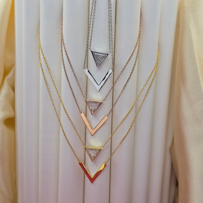 Layered gold, rose-gold, rhodium plated necklace featuring a clear triangular-cut stone pendant on the upper chain and a sleek V-shaped bar pendant on the lower chain, perfect for contemporary everyday styling.