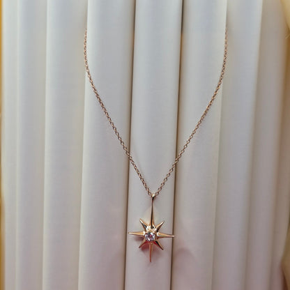 Rose gold, plated chain necklace featuring an eight-point starburst pendant with a clear faceted crystal at the center, offering a celestial and minimal everyday style