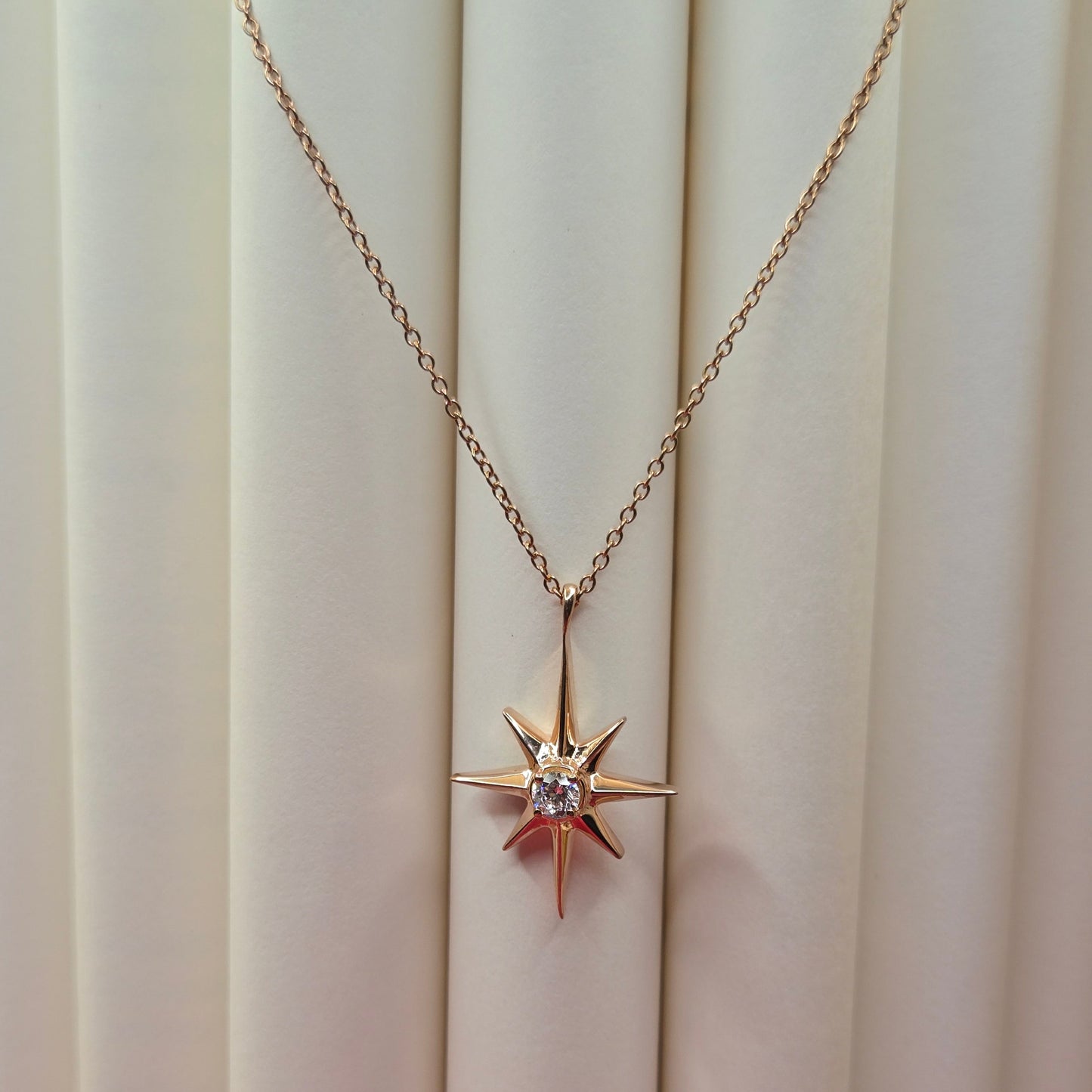 Rose gold, plated chain necklace featuring an eight-point starburst pendant with a clear faceted crystal at the center, offering a celestial and minimal everyday style