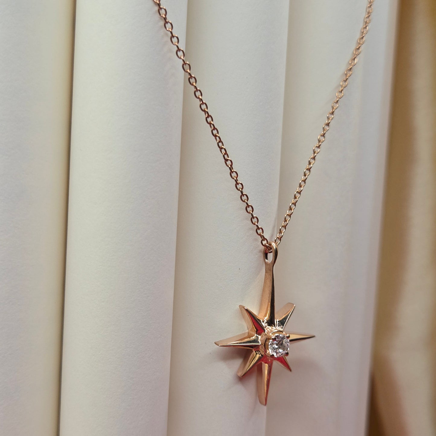 Rose gold, plated chain necklace featuring an eight-point starburst pendant with a clear faceted crystal at the center, offering a celestial and minimal everyday style
