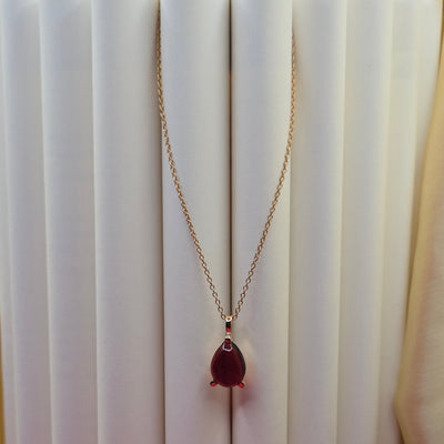 Gold-plated chain necklace featuring a smooth teardrop-shaped deep maroon gemstone pendant, styled against a soft neutral backdrop for an elegant and minimal look.