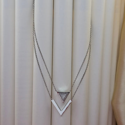 Layered rhodium plated necklace featuring a clear triangular-cut stone pendant on the upper chain and a sleek V-shaped bar pendant on the lower chain, perfect for contemporary everyday styling.