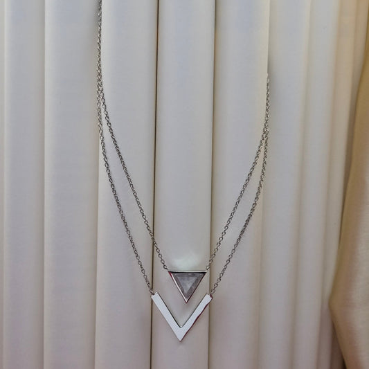 Layered rhodium plated necklace featuring a clear triangular-cut stone pendant on the upper chain and a sleek V-shaped bar pendant on the lower chain, perfect for contemporary everyday styling.