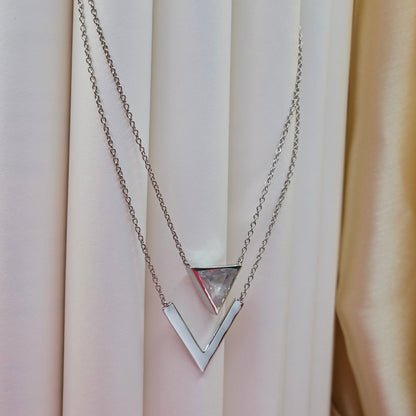 Layered rhodium plated necklace featuring a clear triangular-cut stone pendant on the upper chain and a sleek V-shaped bar pendant on the lower chain, perfect for contemporary everyday styling.