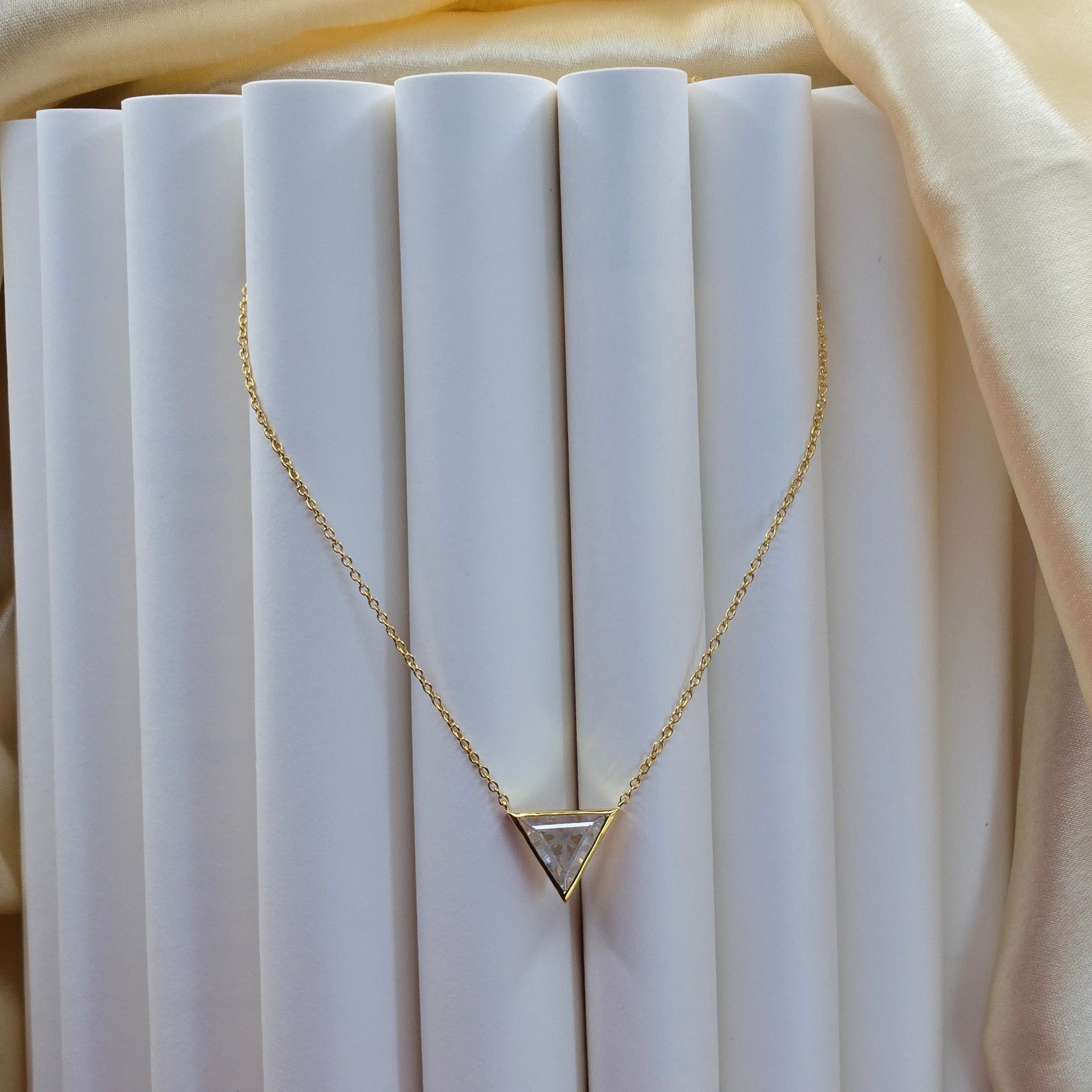 Layered gold plated necklace featuring a clear triangular-cut stone pendant on the upper chain and a sleek V-shaped bar pendant on the lower chain, perfect for contemporary everyday styling.