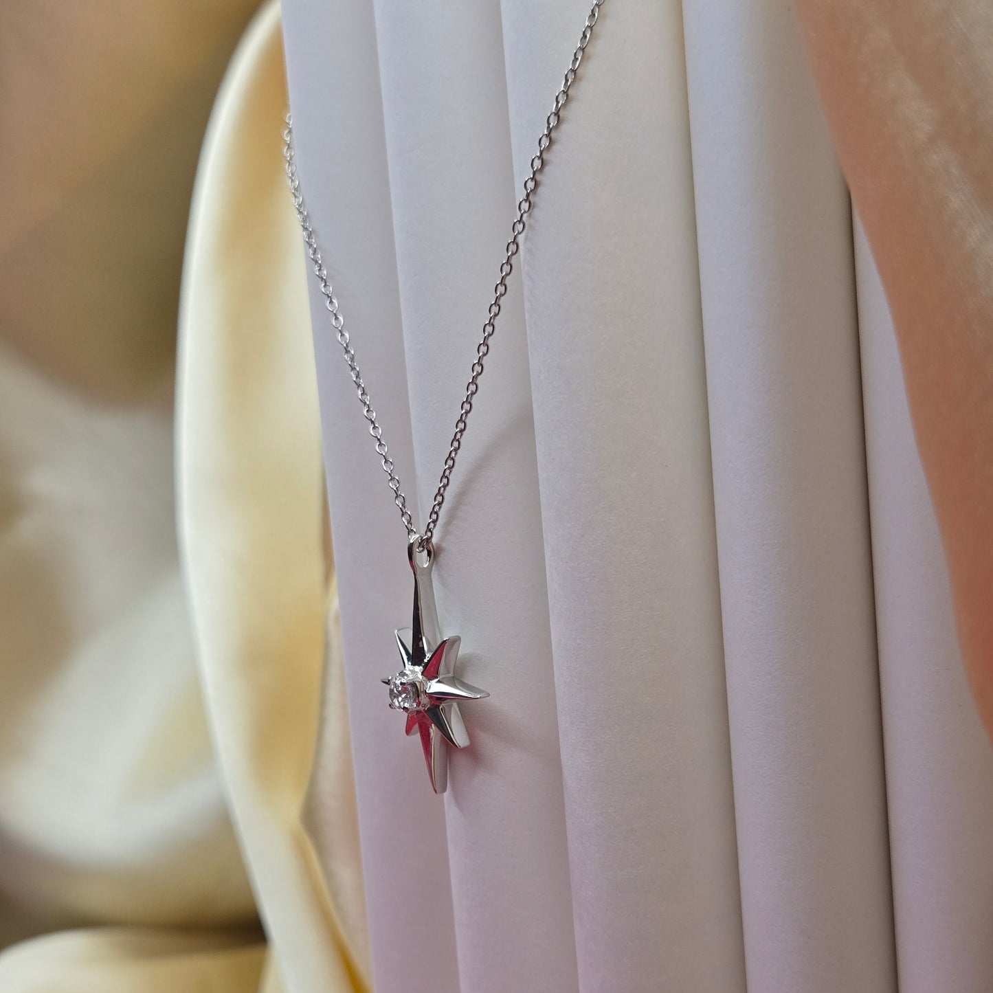 Rhodium plated chain necklace featuring an eight-point starburst pendant with a clear faceted crystal at the center, offering a celestial and minimal everyday style