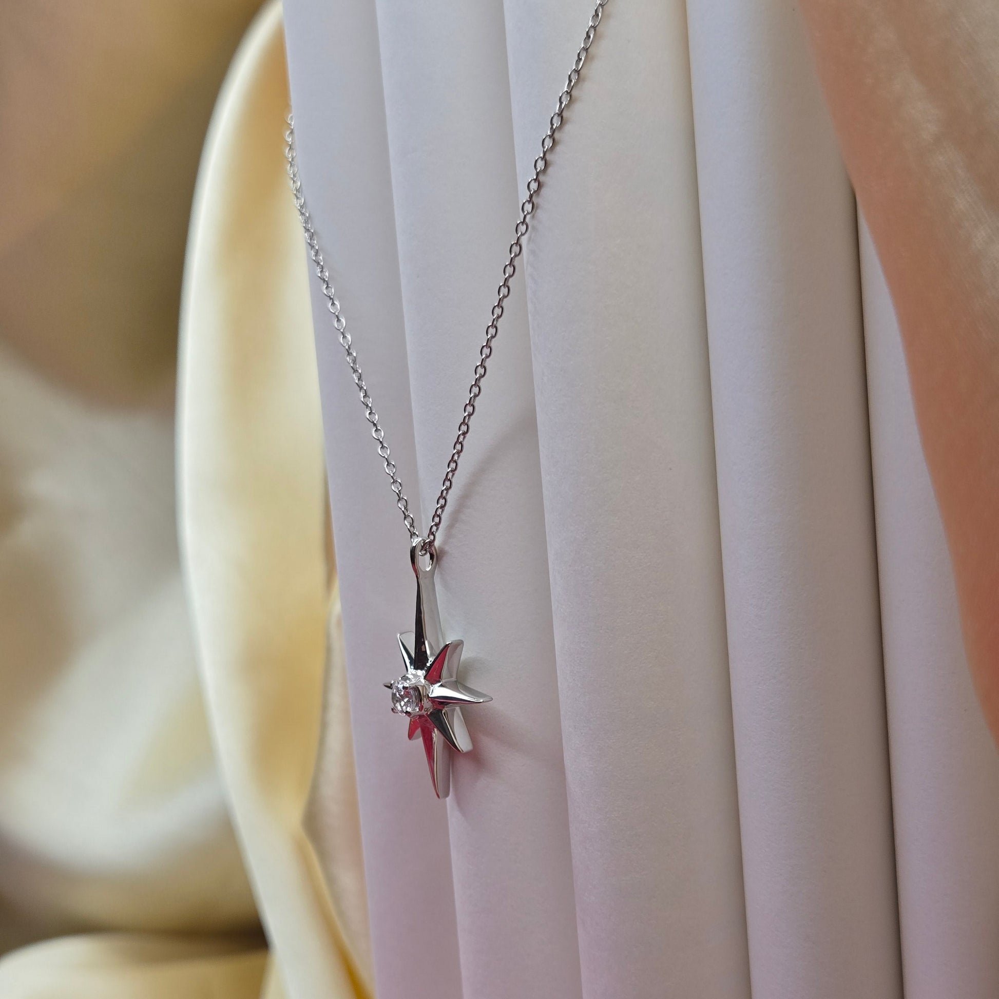 Rhodium plated chain necklace featuring an eight-point starburst pendant with a clear faceted crystal at the center, offering a celestial and minimal everyday style