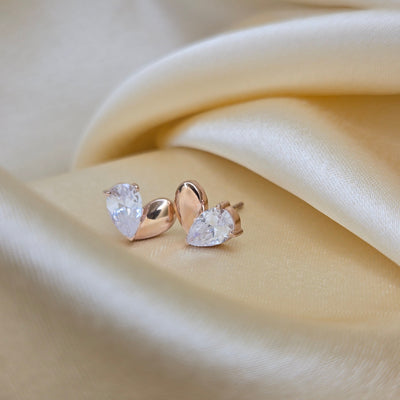 Gold earrings with clear gemstones on a beige fabric background