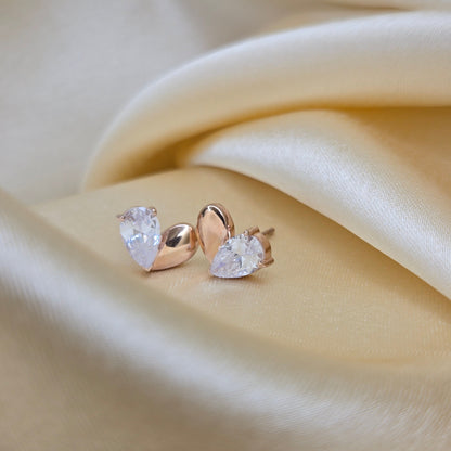 Gold earrings with clear gemstones on a beige fabric background