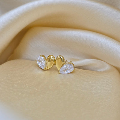 Gold earring with clear gemstones on a beige fabric background