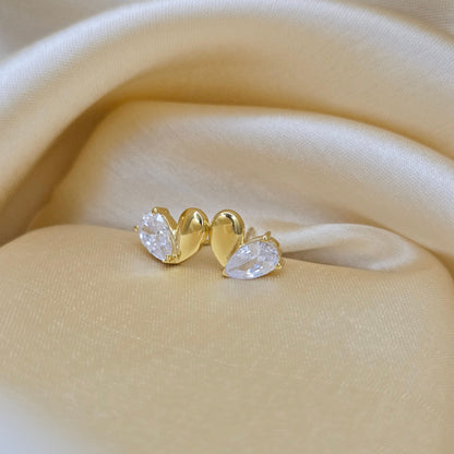 Gold earring with clear gemstones on a beige fabric background