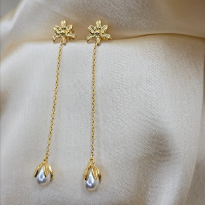 Lightweight gold chain dangle earrings with pearl buds and intricate flower detailing, photographed on luxurious ivory satin for a refined and romantic aesthetic.