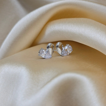 Silver earrings with clear stones on a beige satin background