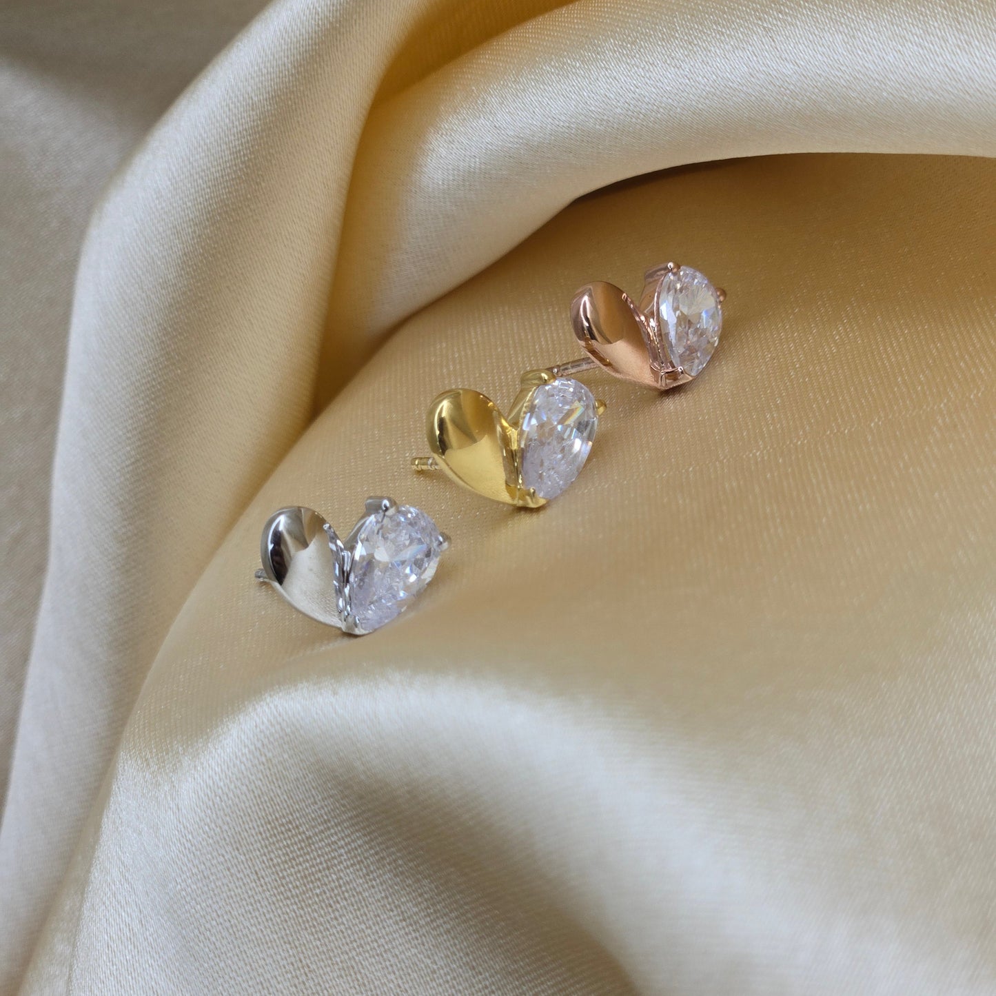 Pair of gold and silver earrings on beige fabric