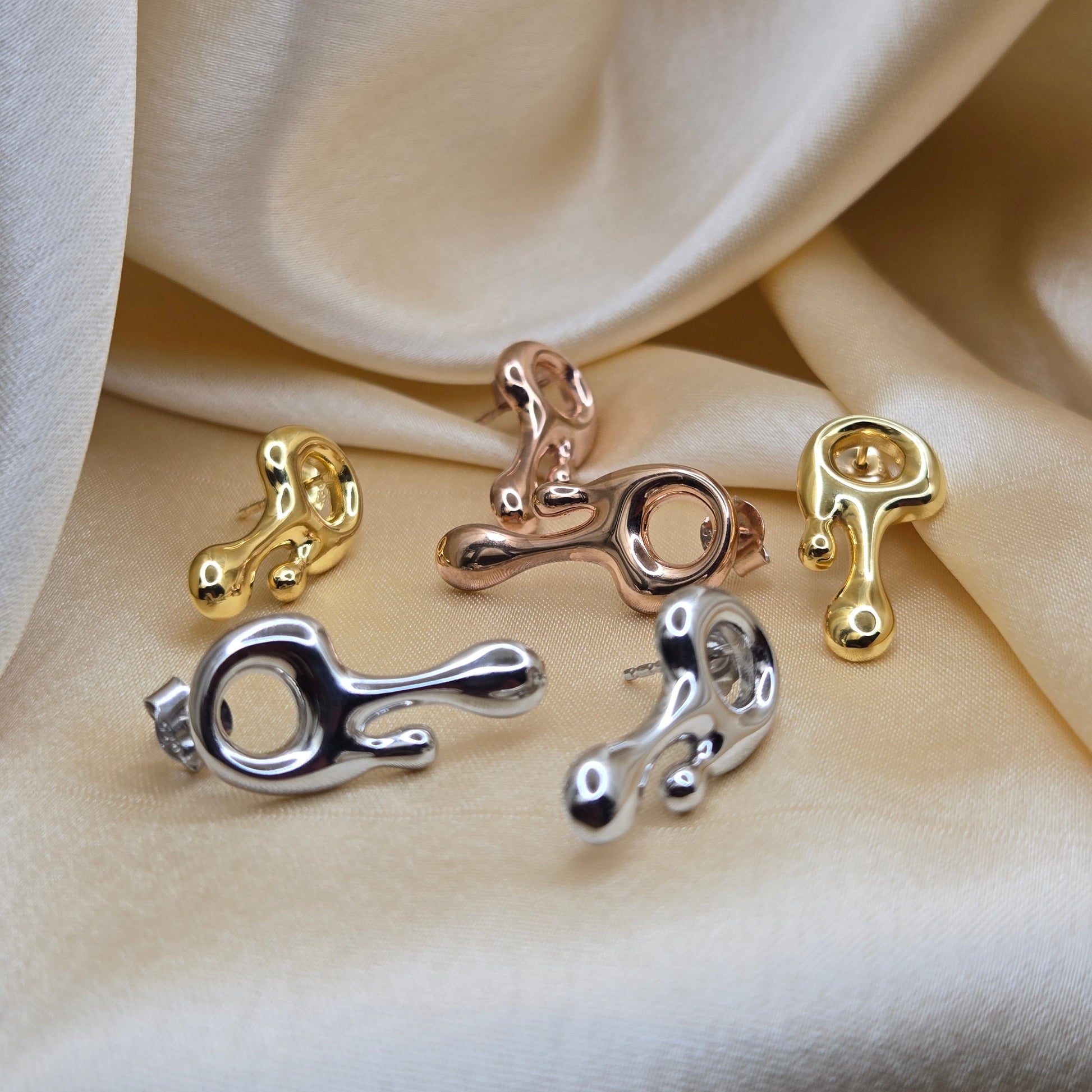 Art-inspired gold, rose-gold & rhodium studs with a melted liquid metal form, offering bold yet elegant statement style for everyday and occasion wear.