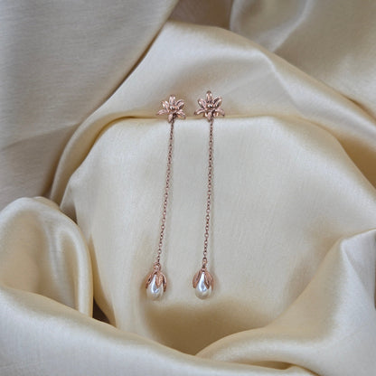 Lightweight rose-gold chain dangle earrings with pearl buds and intricate flower detailing, photographed on luxurious ivory satin for a refined and romantic aesthetic.