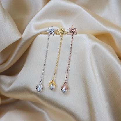 Lightweight gold, rose-gold & rhodium chain dangle earrings with pearl buds and intricate flower detailing, photographed on luxurious ivory satin for a refined and romantic aesthetic.