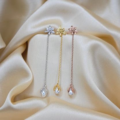 Lightweight gold, rose-gold & rhodium chain dangle earrings with pearl buds and intricate flower detailing, photographed on luxurious ivory satin for a refined and romantic aesthetic.