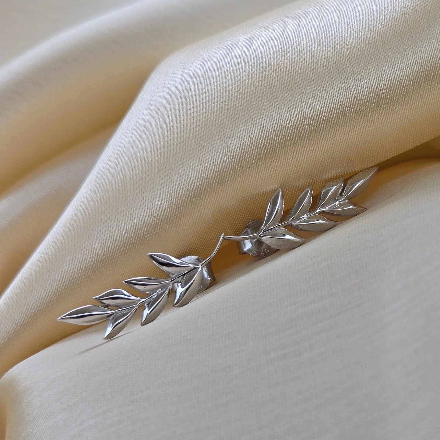 Silver leaf-shaped brooch on beige fabric