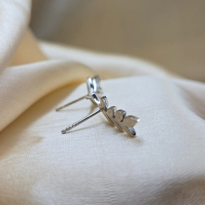 Silver leaf earring on a white fabric background