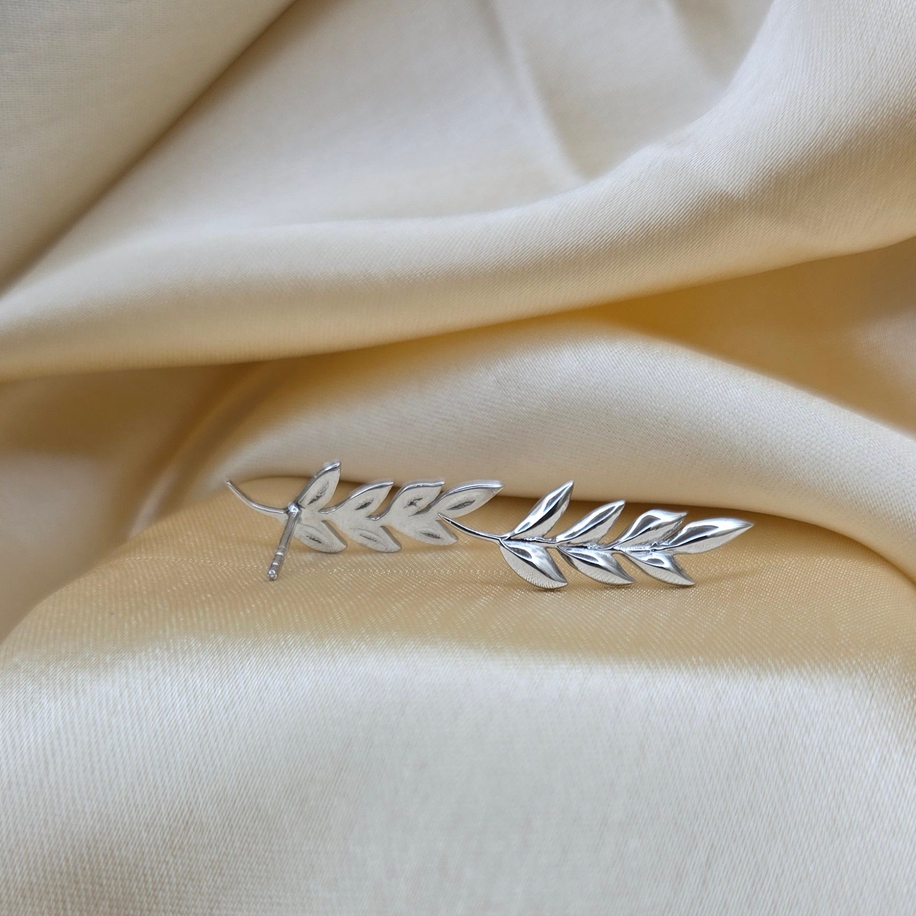 Silver leaf brooch on a beige fabric background