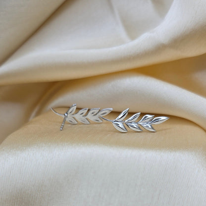 Silver leaf brooch on a beige fabric background