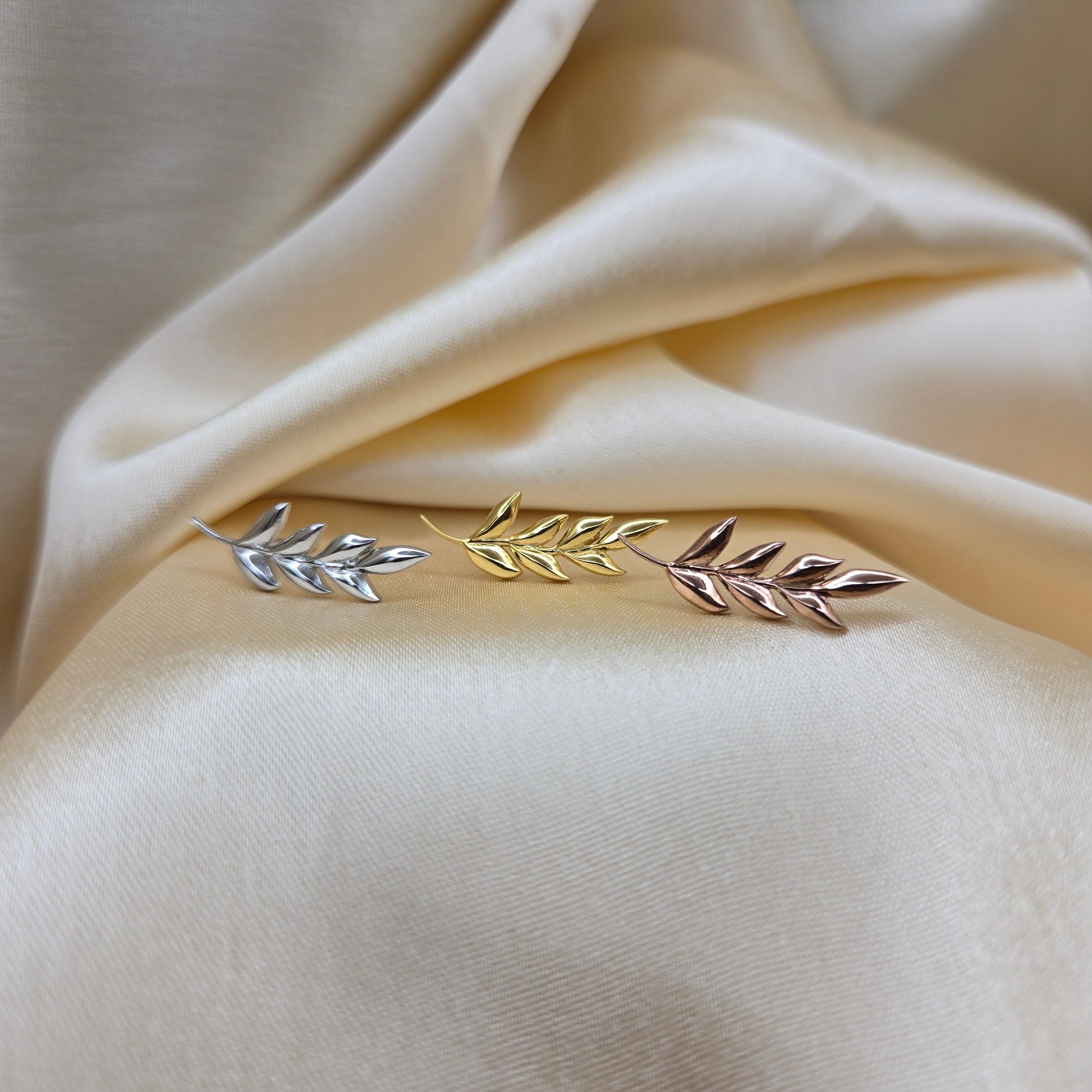 Decorative brooch with leaf design on a beige fabric background