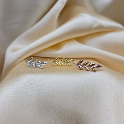 Decorative brooch with leaf design on a beige fabric background