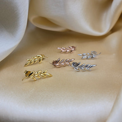 Set of gold and silver leaf-shaped earrings on beige fabric