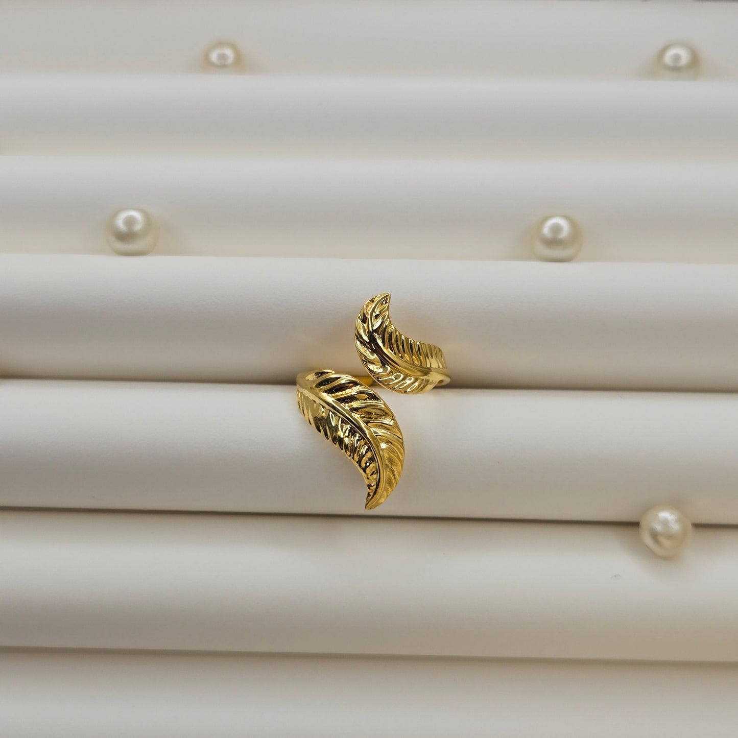 Elegant botanical-inspired ring with twin leaf accents, adjustable fit, and a polished gold tone, perfect for daily wear or stacking.