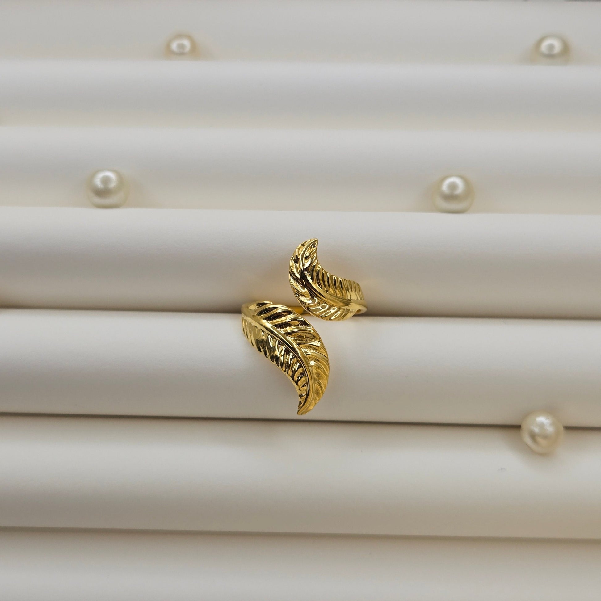 Elegant botanical-inspired ring with twin leaf accents, adjustable fit, and a polished gold tone, perfect for daily wear or stacking.