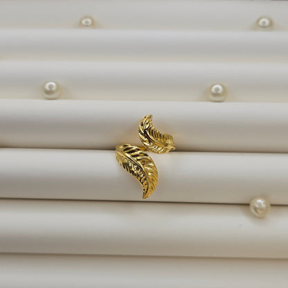 Elegant botanical-inspired ring with twin leaf accents, adjustable fit, and a polished gold tone, perfect for daily wear or stacking.