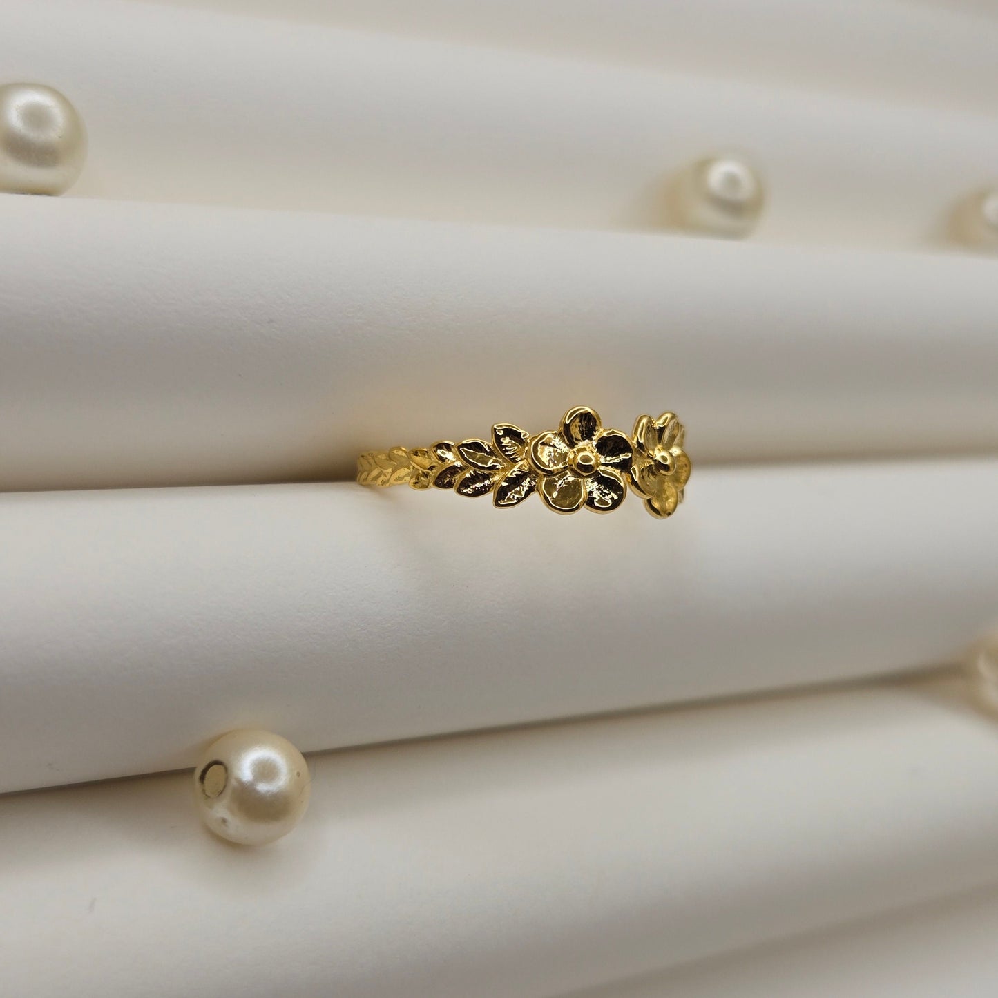 Minimalistic gold-tone flower band ring with smooth petal detailing, perfect for stacking or wearing as a subtle statement piece.