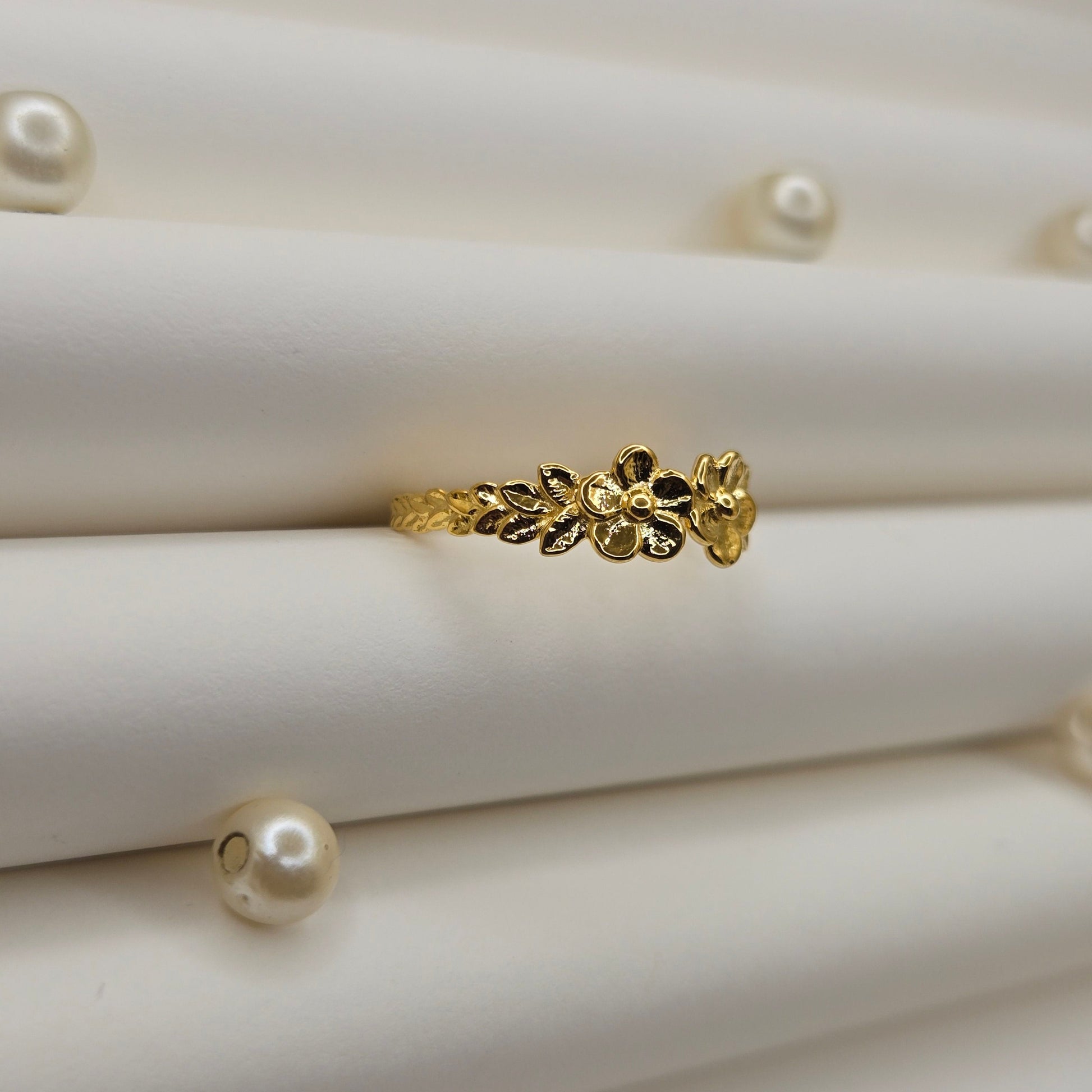 Minimalistic gold-tone flower band ring with smooth petal detailing, perfect for stacking or wearing as a subtle statement piece.