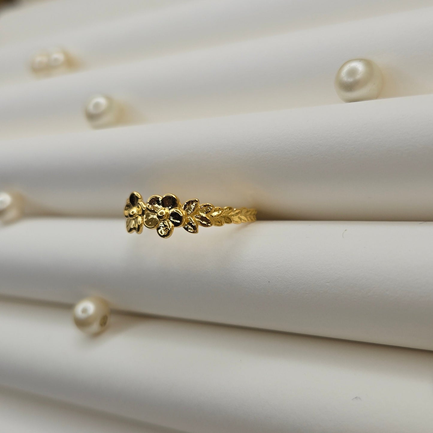 Minimalistic gold-tone flower band ring with smooth petal detailing, perfect for stacking or wearing as a subtle statement piece.