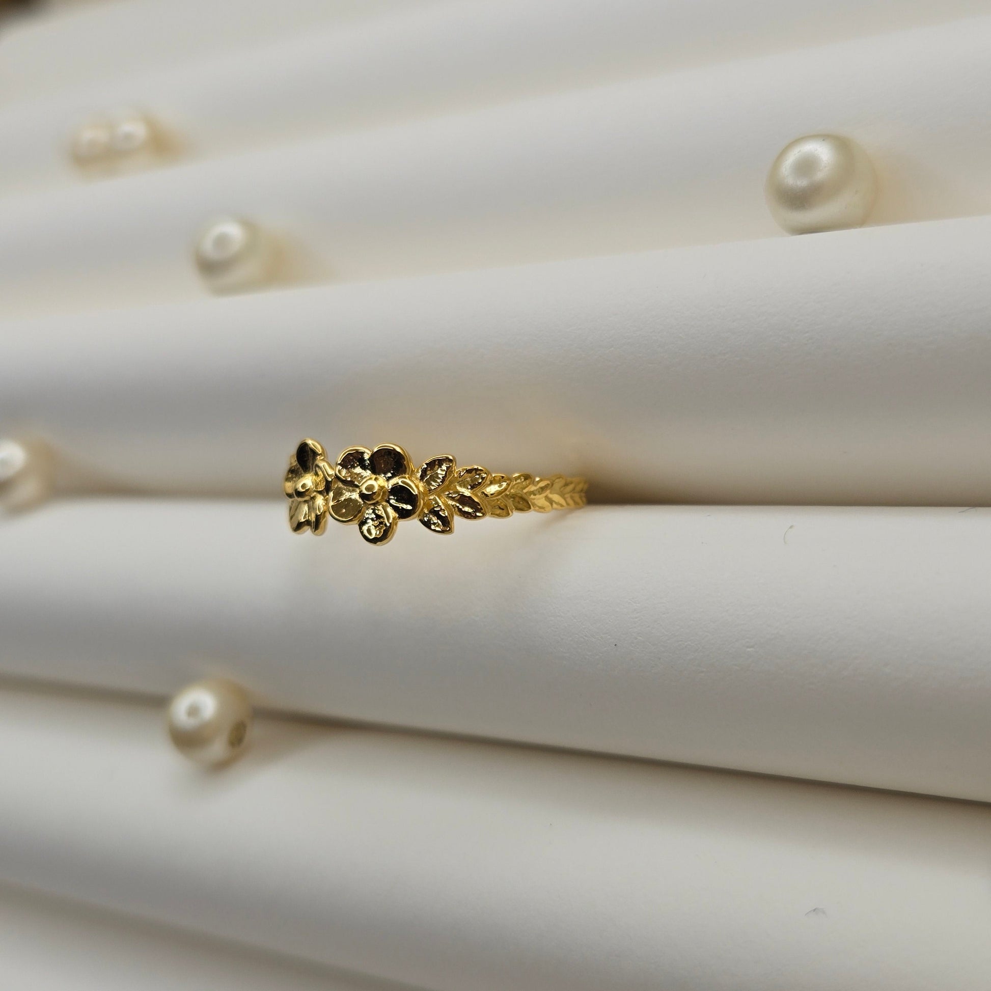 Minimalistic gold-tone flower band ring with smooth petal detailing, perfect for stacking or wearing as a subtle statement piece.