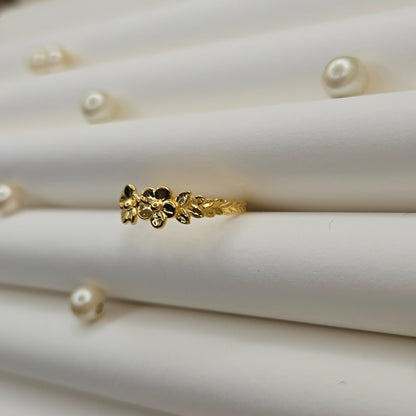 Minimalistic gold-tone flower band ring with smooth petal detailing, perfect for stacking or wearing as a subtle statement piece.