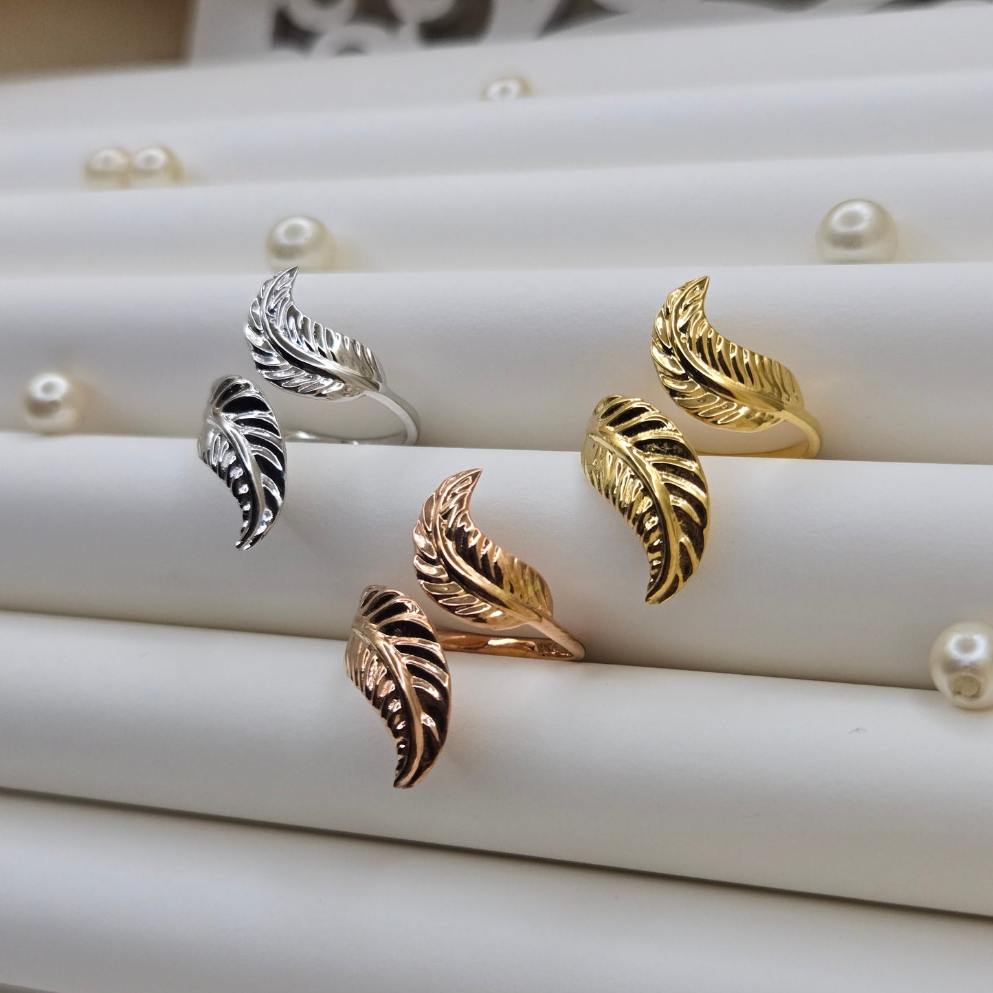 Elegant botanical-inspired ring with twin leaf accents, adjustable fit, and a polished gold, rose-gold, and rhodium stone, perfect for daily wear or stacking.