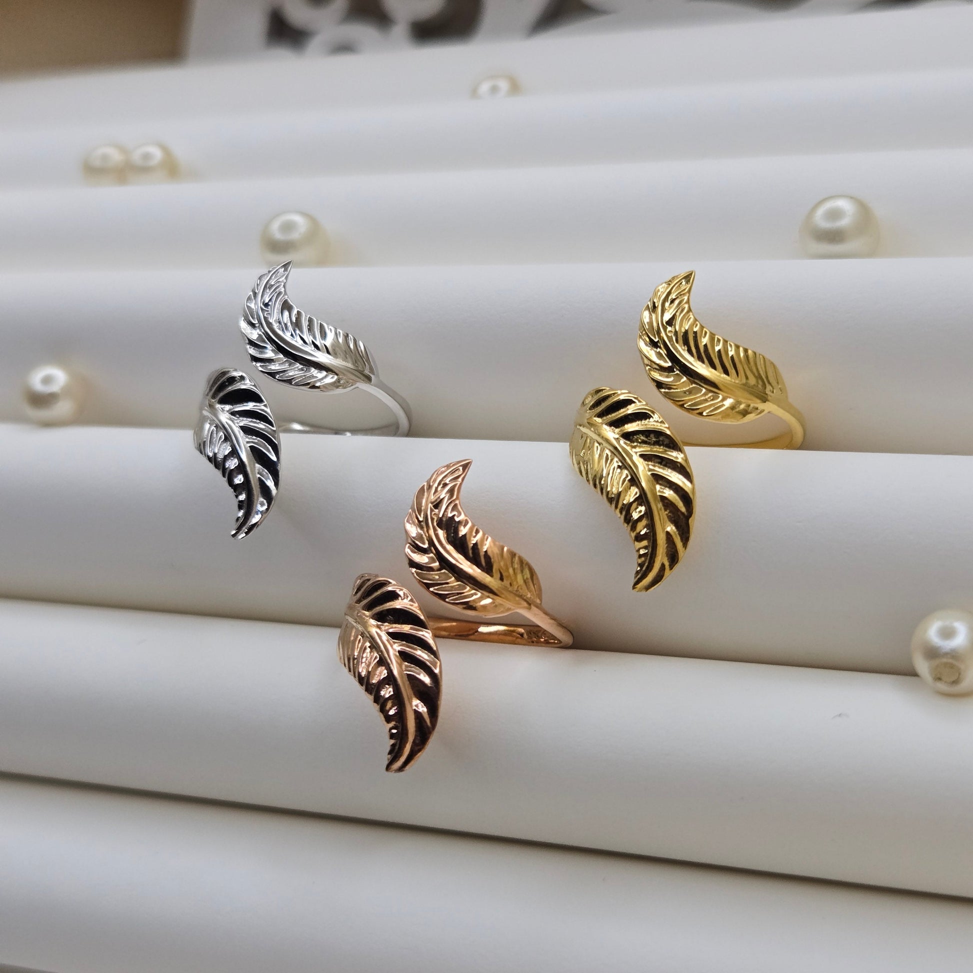 Elegant botanical-inspired ring with twin leaf accents, adjustable fit, and a polished gold, rose-gold, and rhodium stone, perfect for daily wear or stacking.