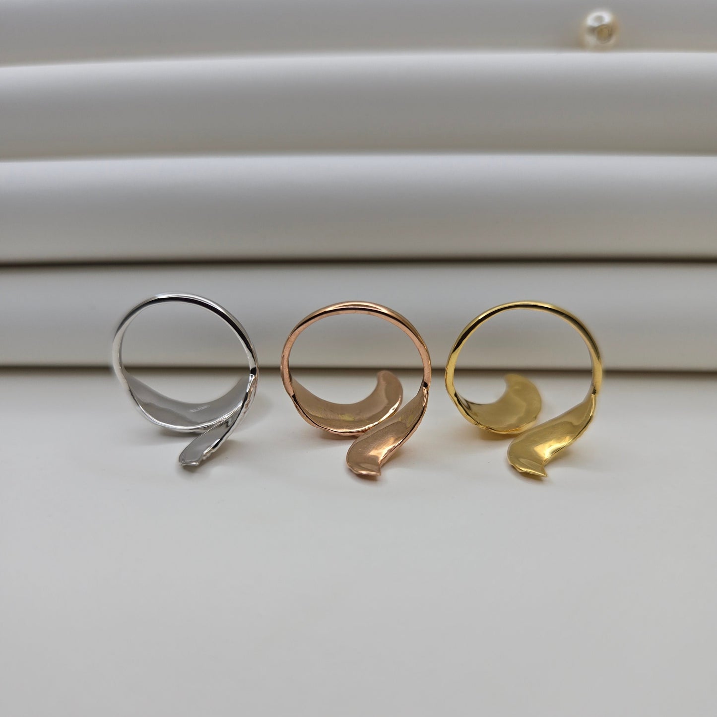 Elegant botanical-inspired ring with twin leaf accents, adjustable fit, and a polished gold, rose-gold, and rhodium stone, perfect for daily wear or stacking.