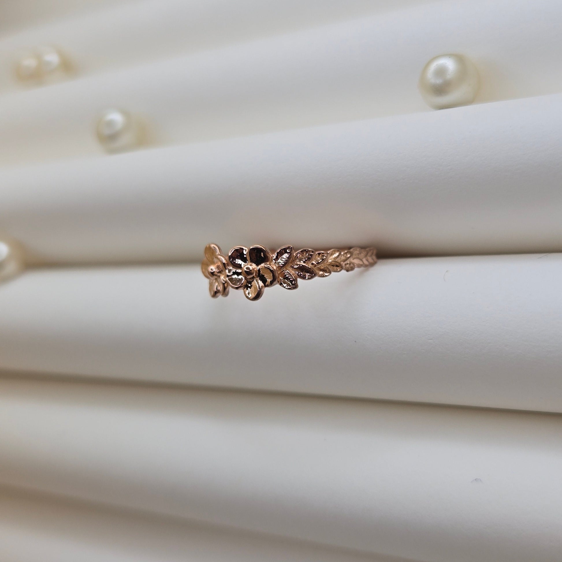 Minimalistic rose gold-tone flower band ring with smooth petal detailing, perfect for stacking or wearing as a subtle statement piece.