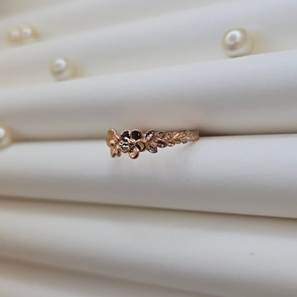 Minimalistic rose gold-tone flower band ring with smooth petal detailing, perfect for stacking or wearing as a subtle statement piece.