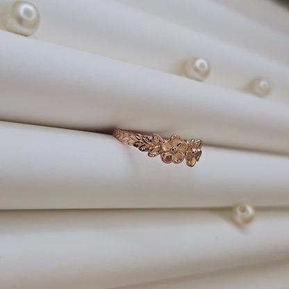 Minimalistic rose gold-tone flower band ring with smooth petal detailing, perfect for stacking or wearing as a subtle statement piece.