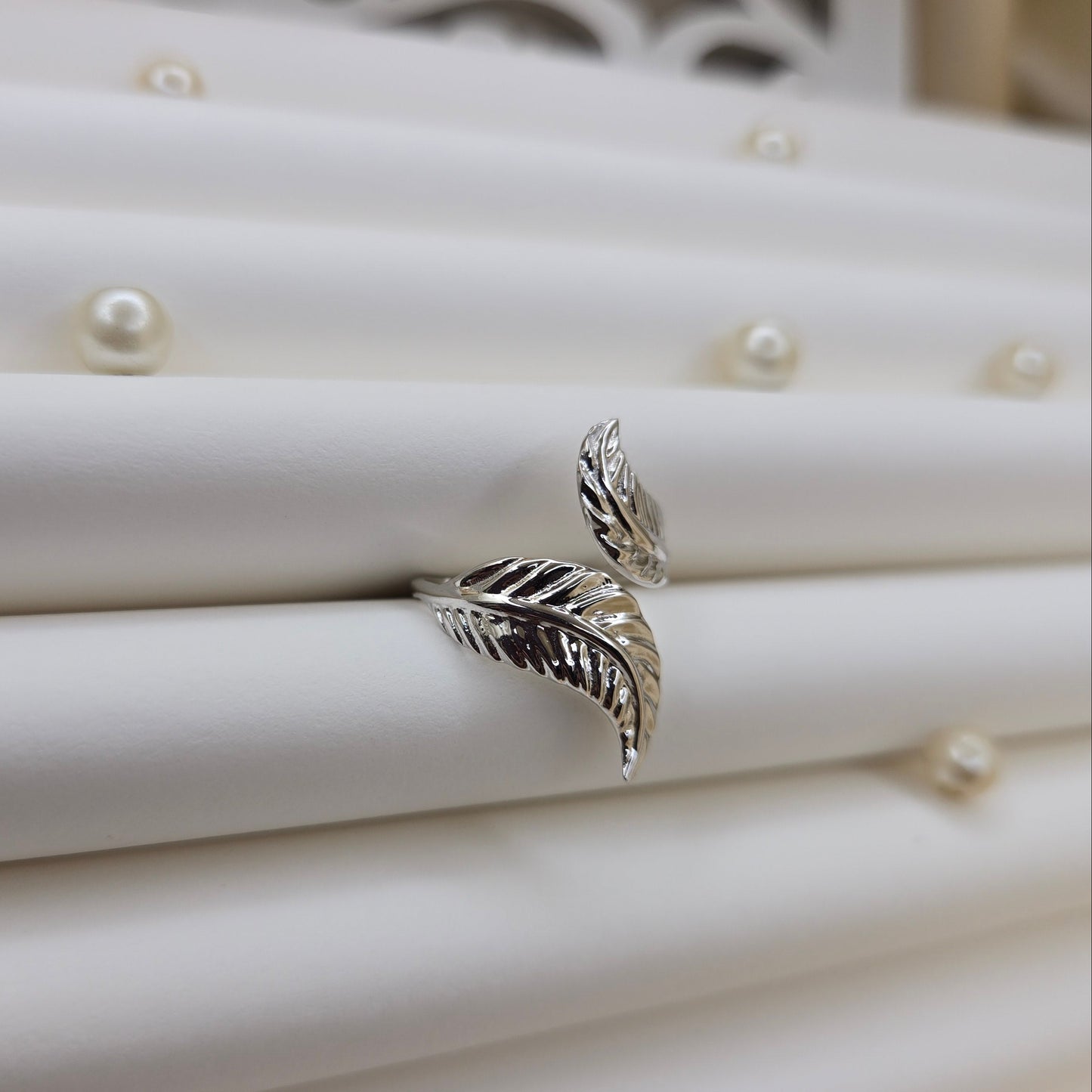 Elegant botanical-inspired ring with twin leaf accents, adjustable fit, and a polished rhodium stone, perfect for daily wear or stacking.