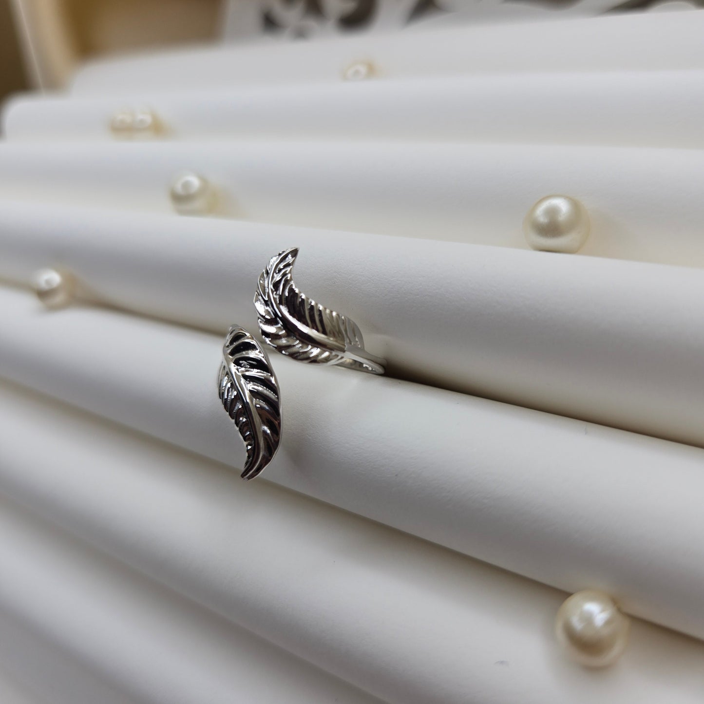 Elegant botanical-inspired ring with twin leaf accents, adjustable fit, and a polished rhodium stone, perfect for daily wear or stacking.