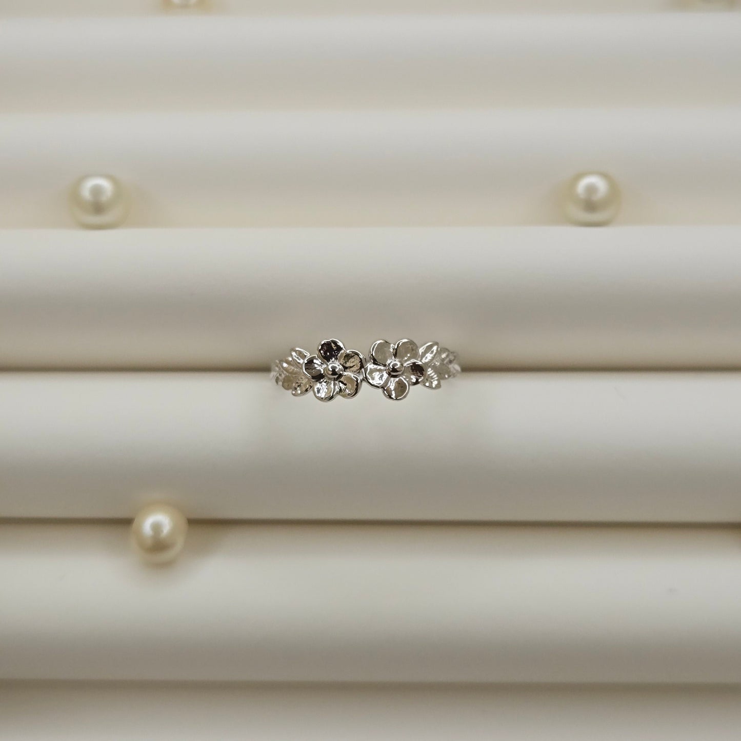 Minimalistic rhodium tone flower band ring with smooth petal detailing, perfect for stacking or wearing as a subtle statement piece.