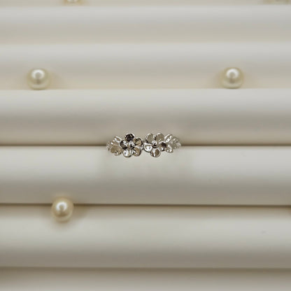 Minimalistic rhodium tone flower band ring with smooth petal detailing, perfect for stacking or wearing as a subtle statement piece.